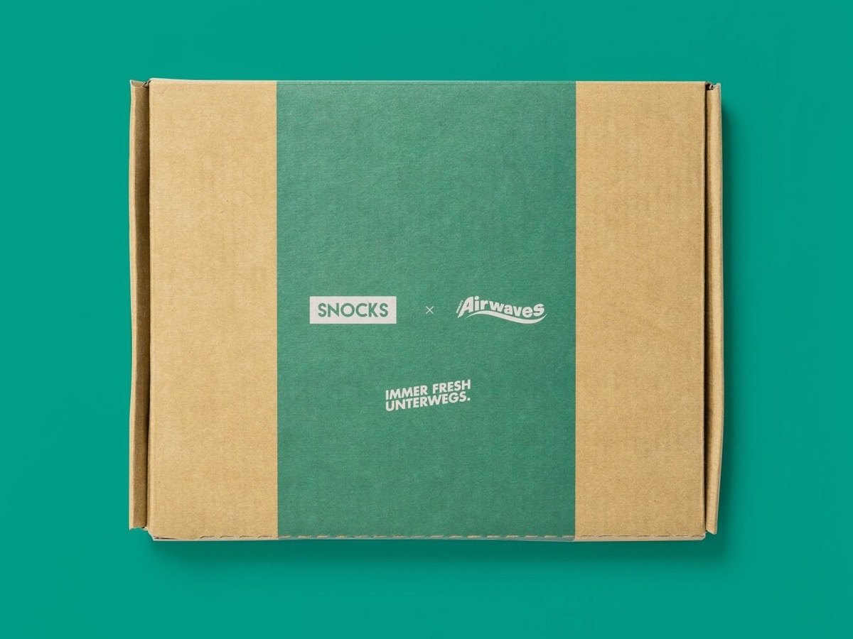 Die Versandbox von Snocks x Airwaves mit dem Aufdruck „Immer fresh unterwegs“ auf mintgrünem Grund