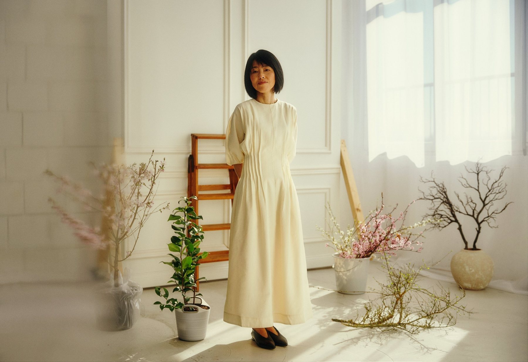 Akiko Kaneko in hellem Kleid in ihrem Atelier zwischen Kirschzweigen